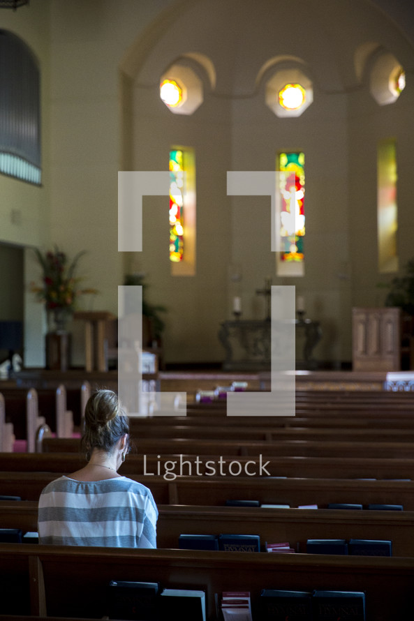 woman in prayer in an empty church