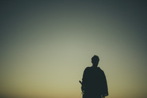 silhouette of a man in a robe and walking stick 