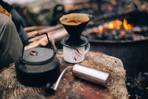 coffee grinder and slow brew coffee by a fire