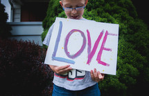 a boy holding a sign with the word love 
