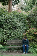 a woman praying on a park bench 
