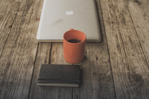 A laptop, notebook and coffee on a wooden table