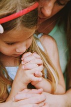 little girl praying being held by her mother