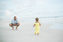 father and toddler daughter on a beach 