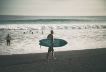 man walking on a beach carrying a surfboard 