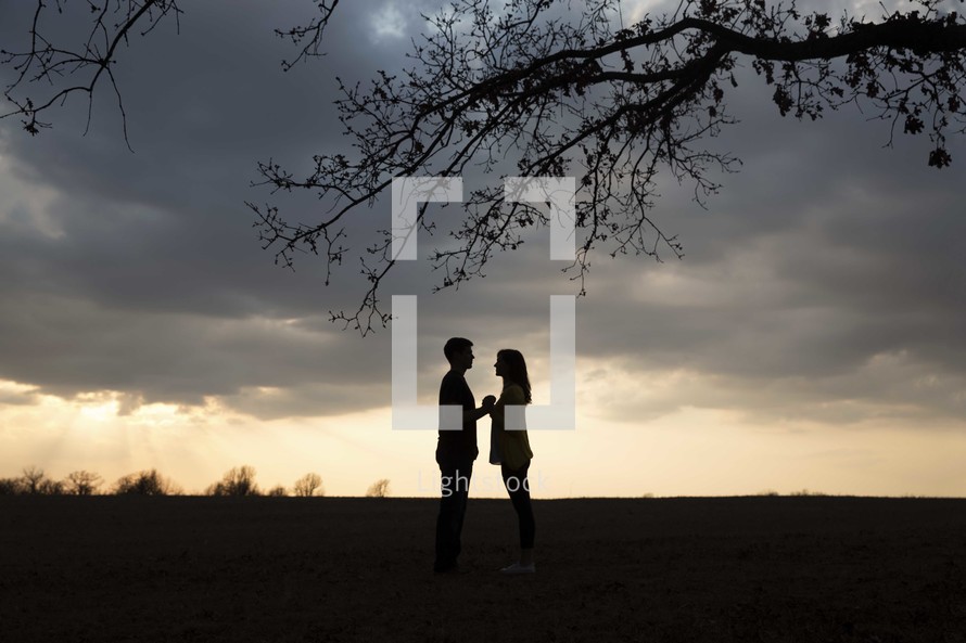 silhouette of a couple holding hands at sunset 