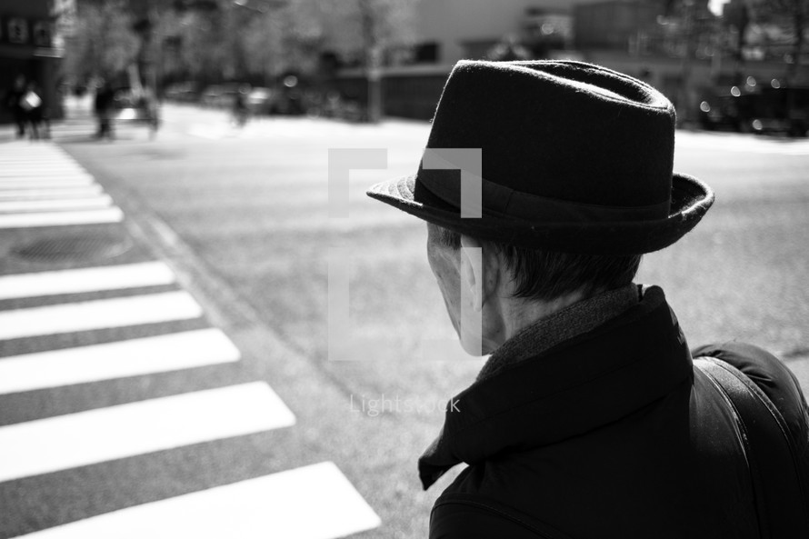 a man in a hat crossing a street in a crosswalk 