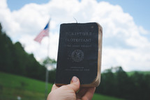 holding up a Bible in front of an American flag 