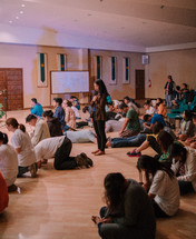 teens sitting on a floor praying during a worship service 