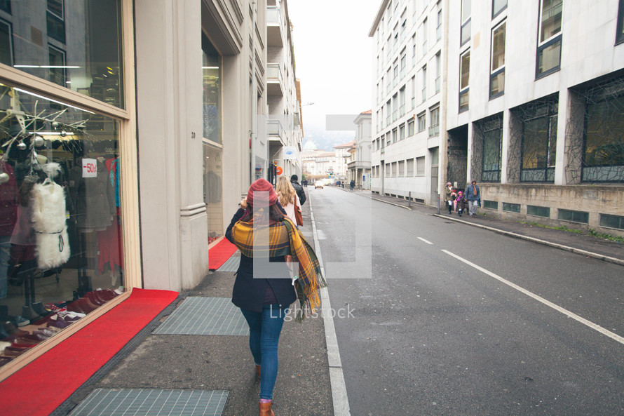 women window shopping walking down a street in Europe 