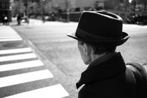 a man in a hat crossing a street in a crosswalk 