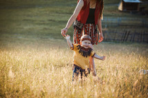 Young Mother with Little Son Kid dressed in Native American Poncho in Summer Field Landscape