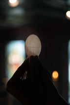 Close up of hands holding up a communion wafer.