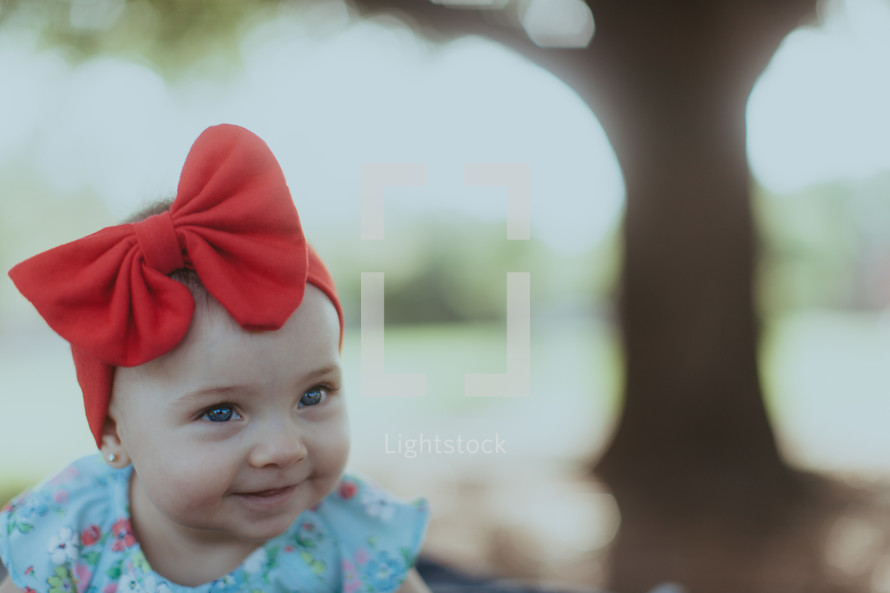 a baby girl with a red headband and bow 