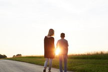 a mother and son holding hands walking on a rural road 