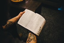 Man's arms holding an open Bible.