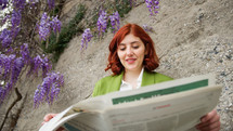 Businesswoman reading newspaper under the wisteria flower