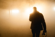 man walking into glowing fog 