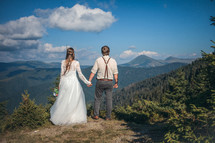 bride and groom standing on a mountaintop 