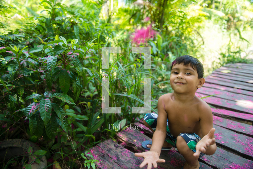 a young boy in a swim suit in a botanical garden 