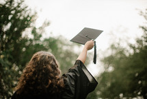 female graduate tossing her graduation cap 