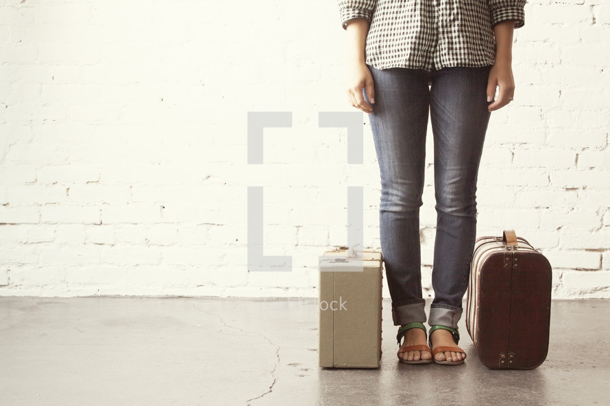 Girl standing ready to go with packed luggage.