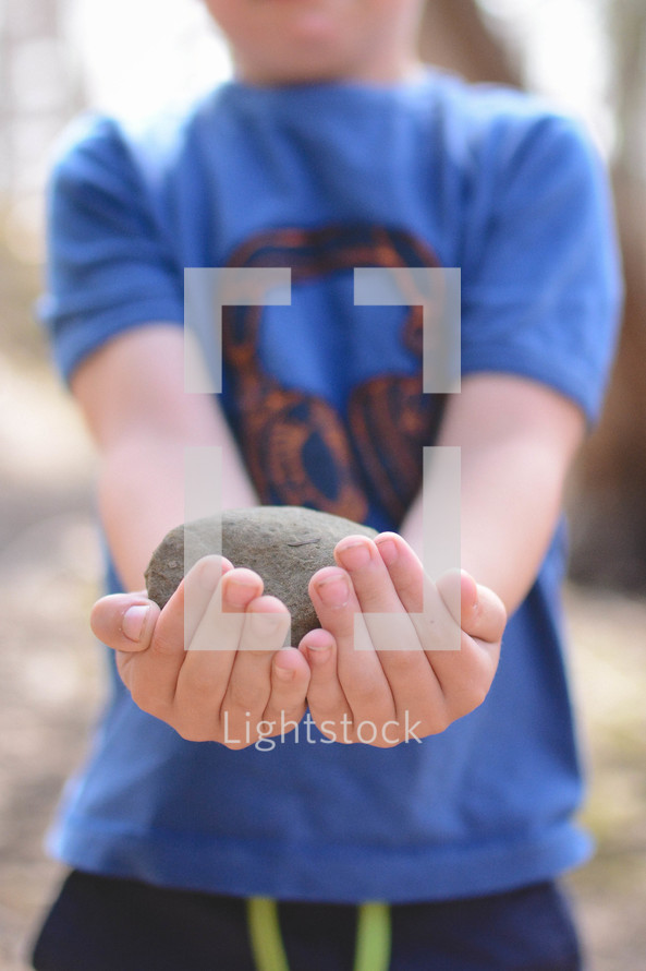 a boy holding a stone 