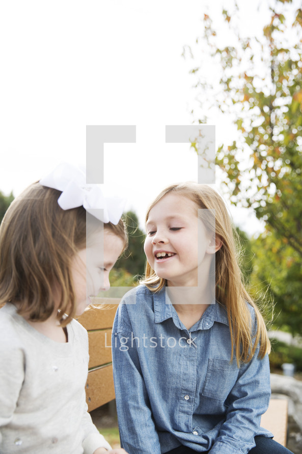 sisters talking while sitting on a park bench