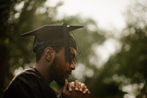 a male graduate praying 
