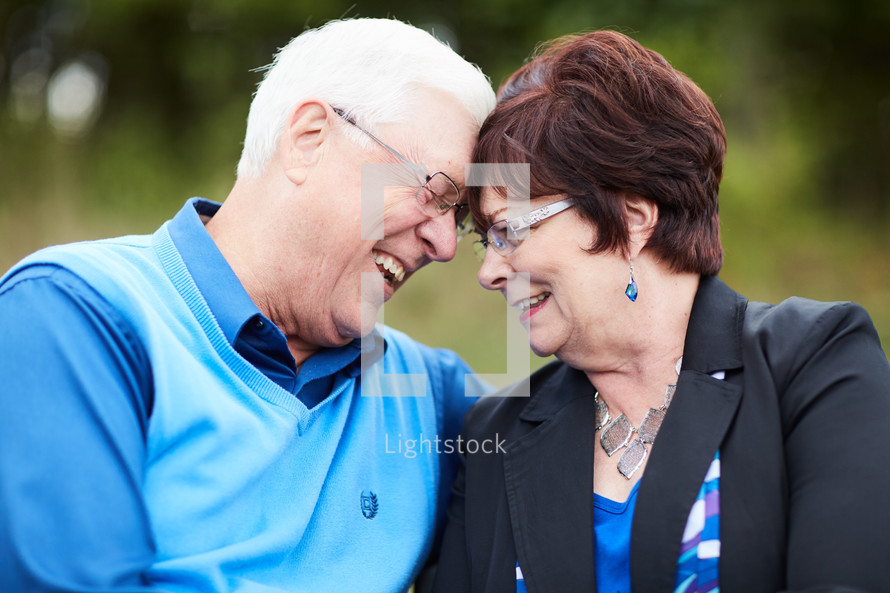 elderly couple sitting on a park bench 