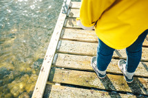 a woman in a yellow raincoat standing on a dock 