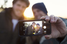 friends taking a selfie together at sunset.