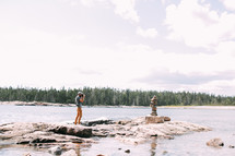 a photographer taking a photograph of stacks rocks along a shore 