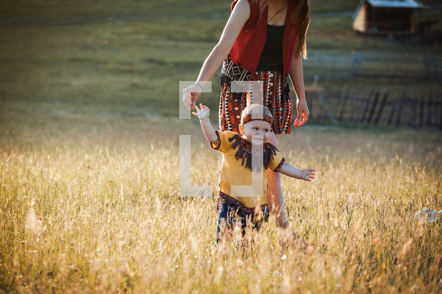 Young Mother with Little Son Kid dressed in Native American Poncho in Summer Field Landscape