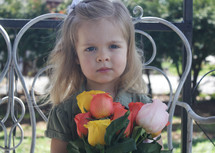 a little girl holding a bouquet of tulips for mom 