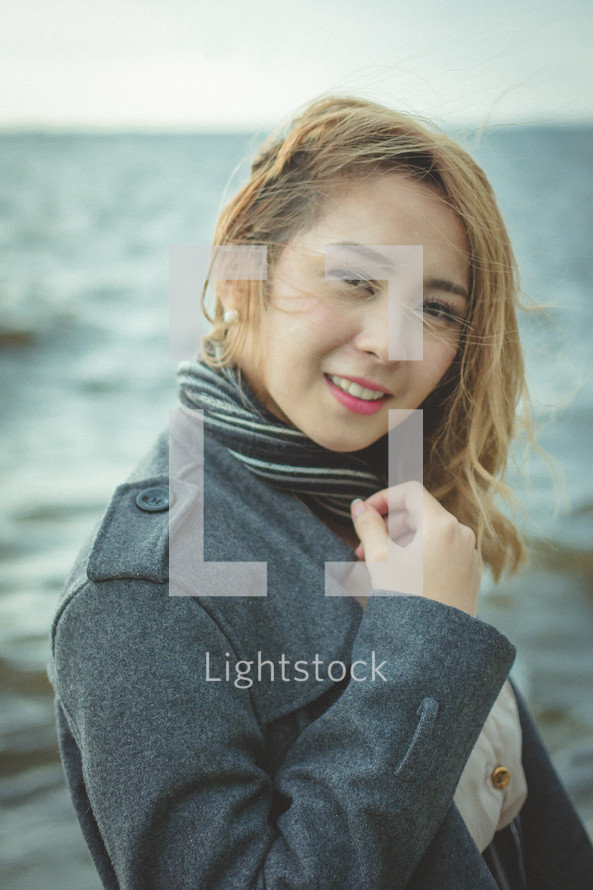face of a young woman standing on a shore 