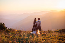 a bride and groom standing outdoors in a mountain landscape 