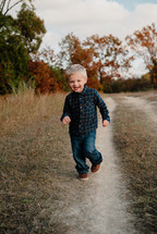 toddler boy running on a dirt road 