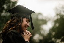 a female praying graduate 