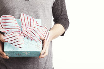 A man holding a blue wrapped gift with a red and white bow