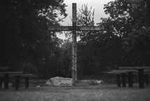 Wooden cross and park benches outside. 