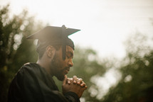 a praying male graduate 