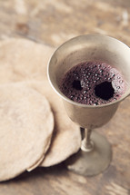 unleavened bread and chalice of wine on wooden table