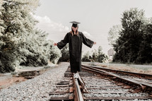graduate balancing walking on train tracks 
