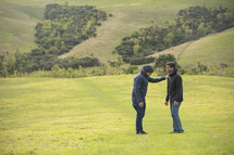 friends praying together in a field of green grass 