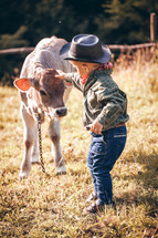 Little Toddler Cowboy Kid with Little Cute Calf the Cow