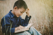 a child reading a Bible outdoors 