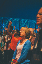 People  standing and worshipping at a church service.