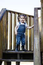 Little girl standing at the top of wooden stairs