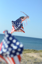 American flag themed kite flying on a beach 